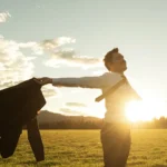Businessman celebrating life standing in green meadow stock photo