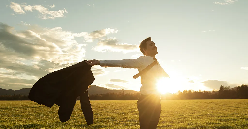 Businessman celebrating life standing in green meadow stock photo
